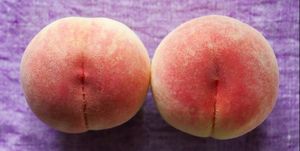 Two peaches on purple linen cloth
