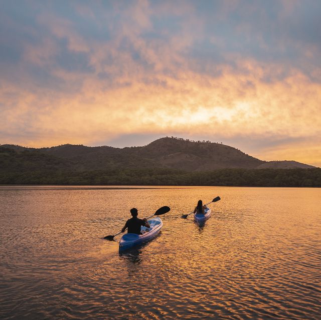 two people kayaking in a lagoon at sunset
