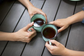 two people seated at a table, drinking coffee, viewed from above 