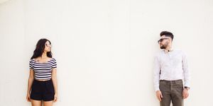 two people standing on white wall background