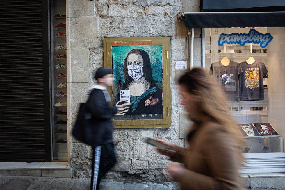 the graffiti artist tv boy paints a mona lisa with a mobile phone and a mask called ‘mobile world virus’ in barcelona