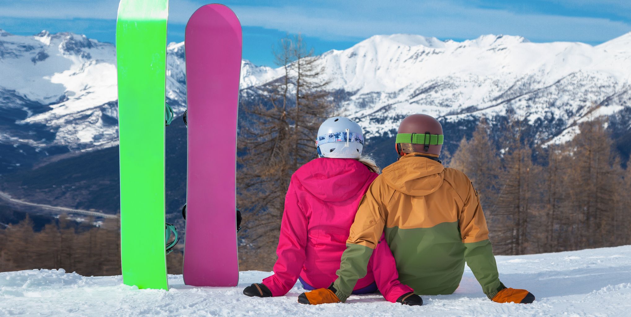 Two people with snowboards enjoying the view of the Alps