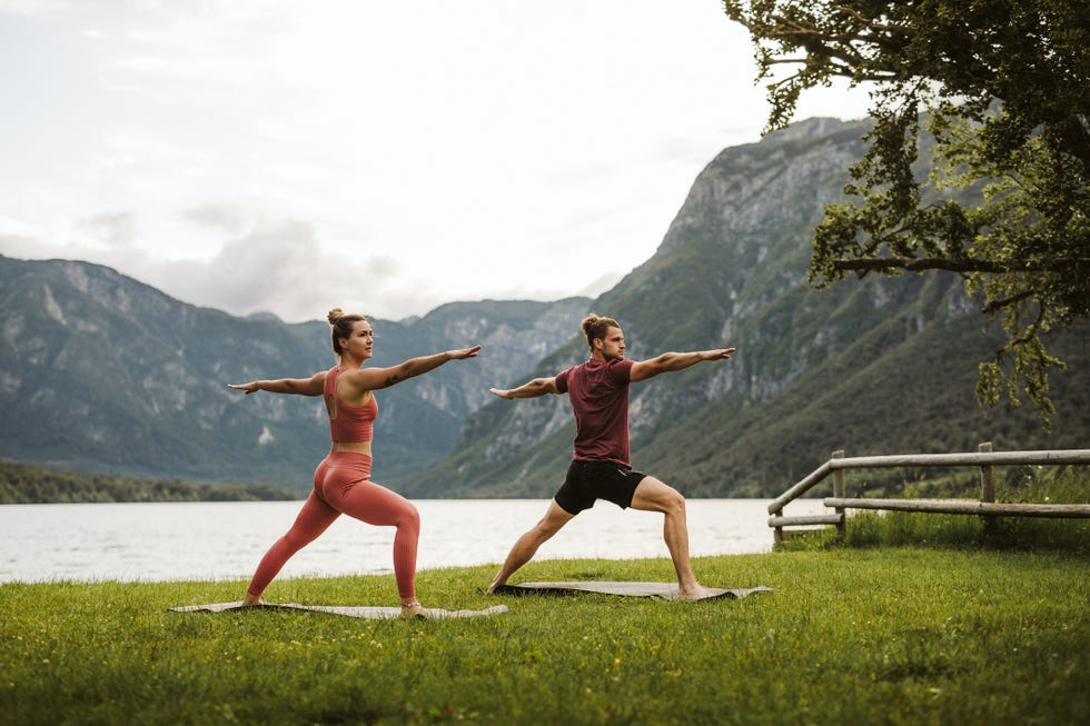 dos personas practicando yoga a la orilla de un lago