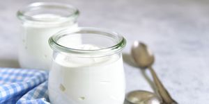 two portions of fresh natural  homemade organic yogurt in a glass jar on a light slate background
