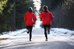 two runners on forest road in winter