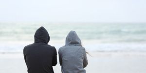 Two sad teenagers sitting on the beach