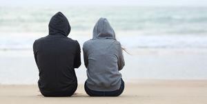 Two sad teenagers sitting on the beach
