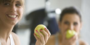 two smiling women eating apples defocused
