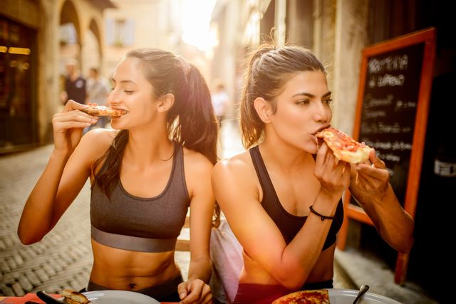 two sporty woman eating pizza