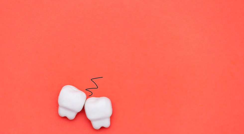 two teeth on red background, bruxism concept flat lay composition, copy space