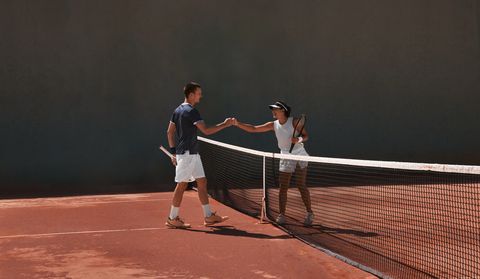 two tennis players fist bumping after match on clay court