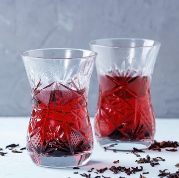 two traditional asian style glasses with hibiscus tea karkade, served with dry hibiskus over blue and gray textured background with space for text