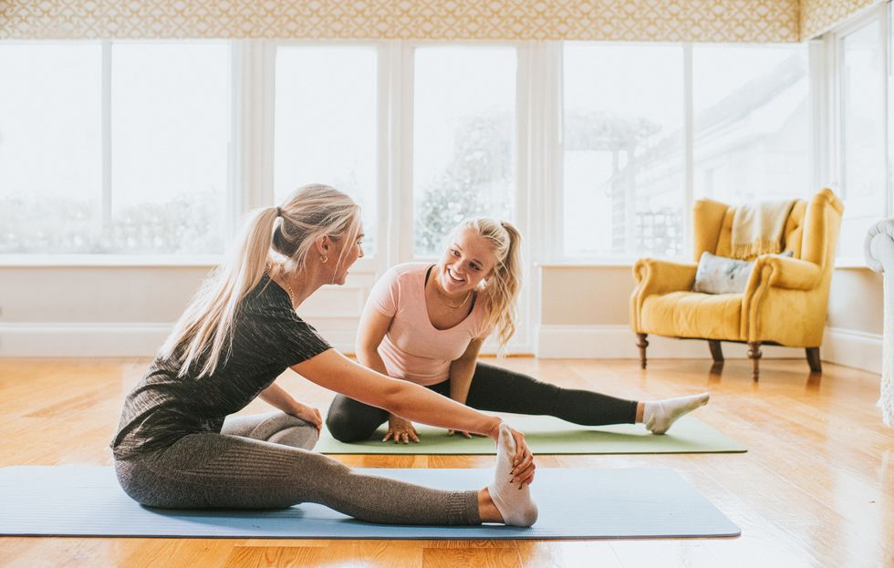 two woman stretch in a home environment