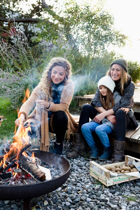 Two women and a girl sitting and relaxing by a fire pit