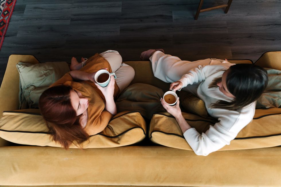 two friend drinking coffee together on couch