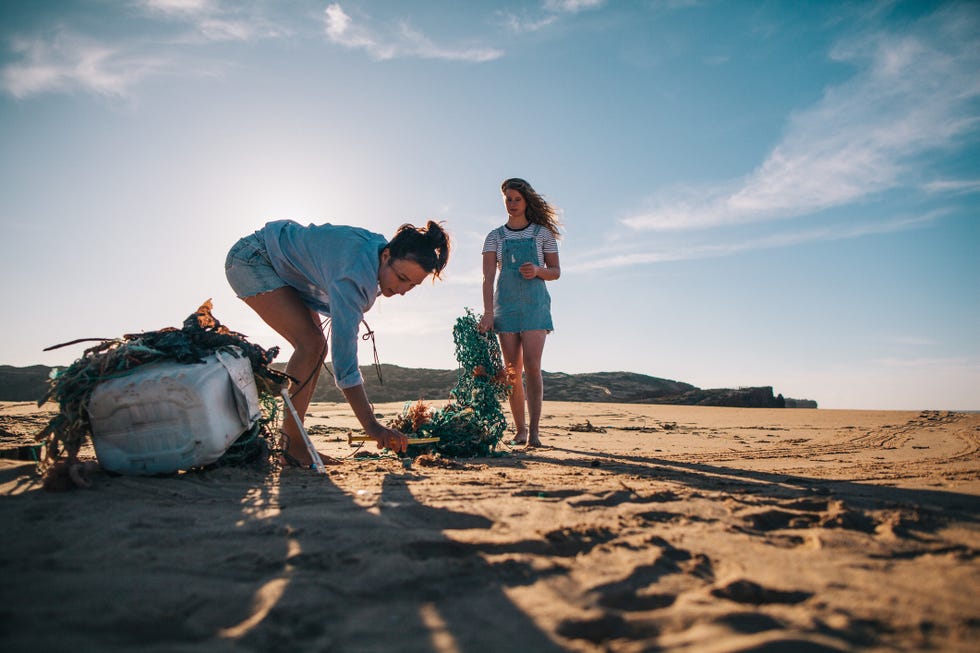 two women collecting garbage on the beach