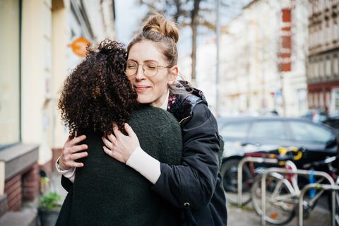 two women greeting one another in the street