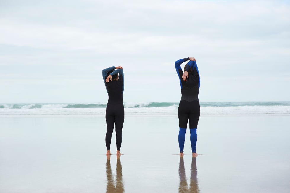 two female sea swimmers stretching on an atlantic beach