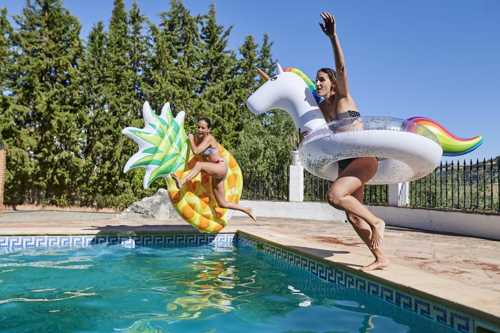 two women jumping into the pool with float