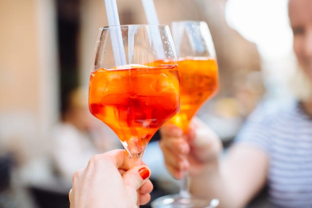 Two women raising a glass of aperol spritz, Ferarra, Italy