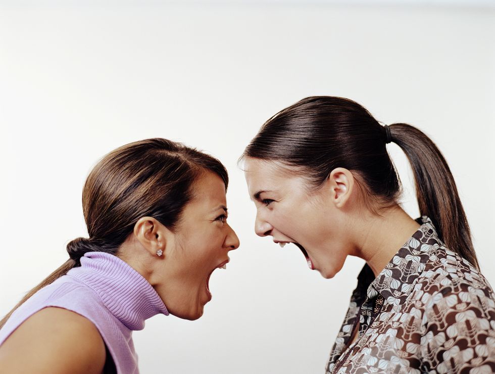 Two young female business associates yelling at each other, profile