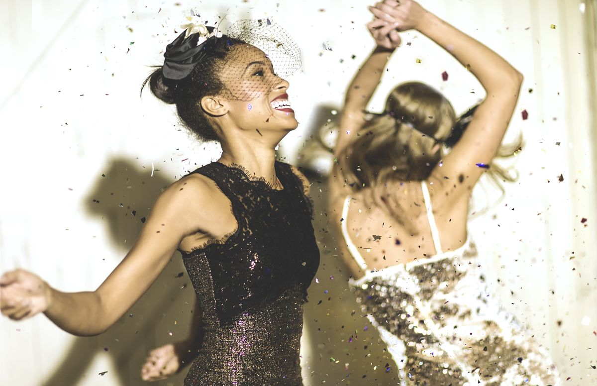 two young women dancing with confetti falling