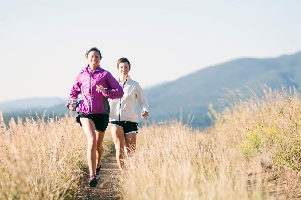Two young women trail running in the mountains on an early morning.