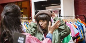 Two young women trying on beret at vintage clothes stall
