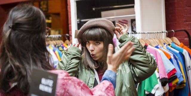 Two young women trying on beret at vintage clothes stall