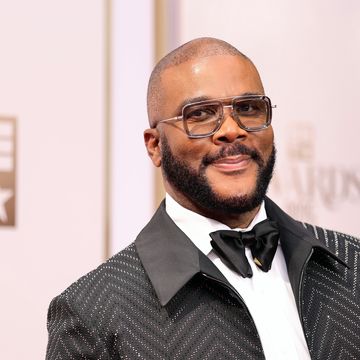 man in a tuxedo and bowtie with chunky frame glasses smiles as he looks left