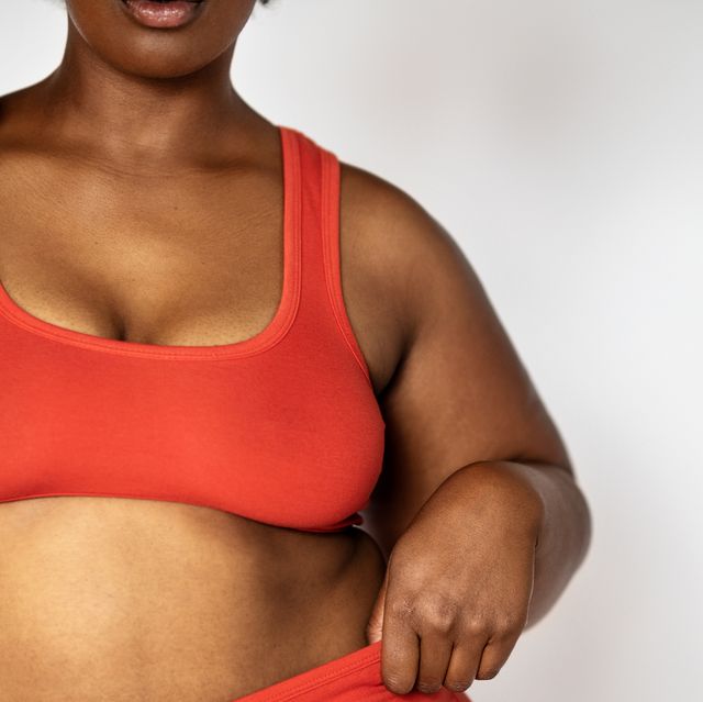 woman wears matching red underwear set as she adjusts strap or bra