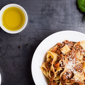 pappardelle, a ribbon shaped type of pasta, served with thick meat sauce, garnished with shredded parmesan and basil leaves