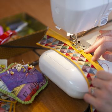 a person working with a sewing machine and multi coloured fabric, close up