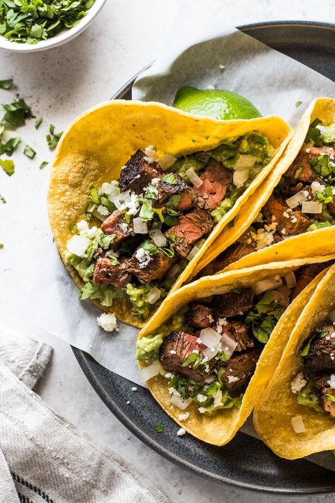 carne asada tacos with guacamole on paper and grey plate
