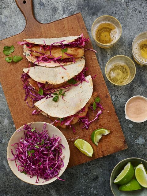 fried fish tacos on wood board with red cabbage