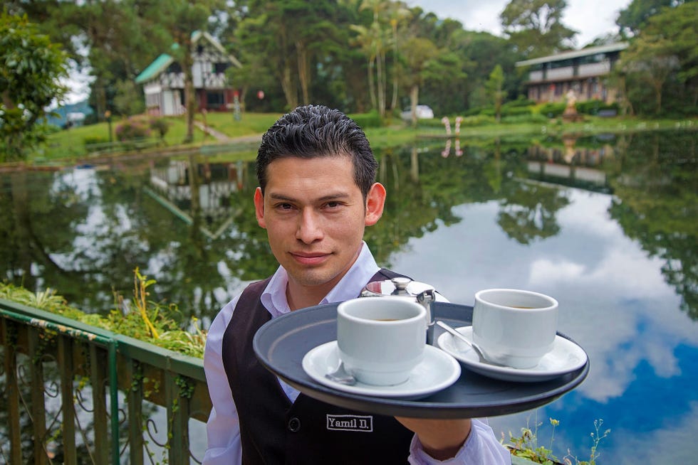 Yamil Diaz poseert bij restaurant Selva Negra met kopjes biologische koffie van La Hammonia