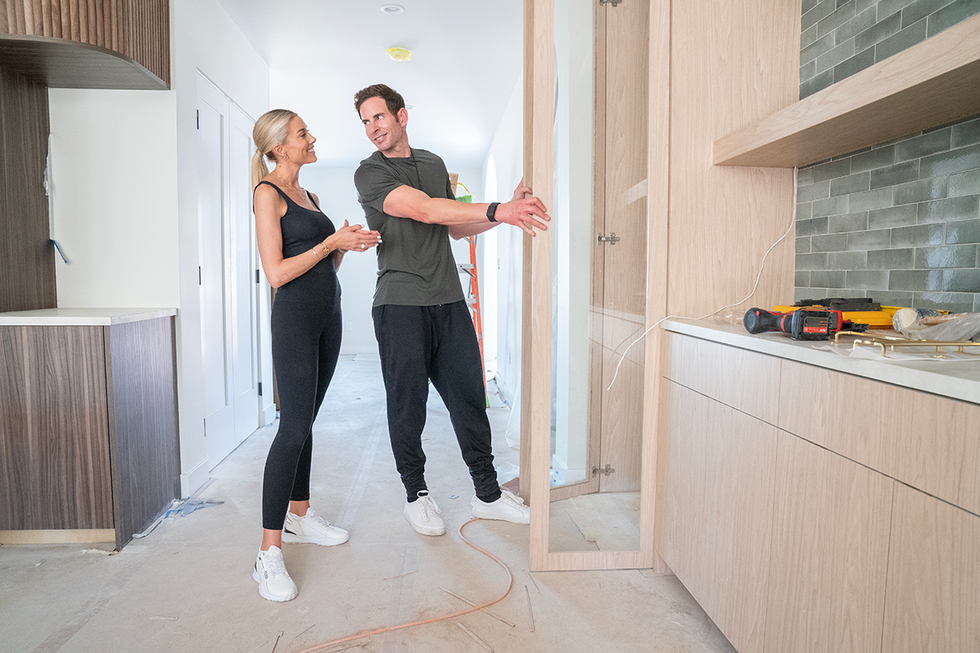 two individuals discussing a cabinet installation in a home under renovation