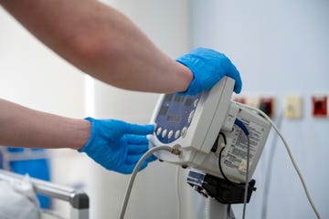 a healthcare professional is operating a medical device with gloved hands inside a clinical setting