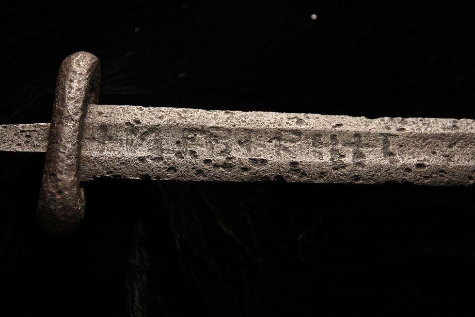 Closeup van de inscriptie VLFBERHT Ulfberht op een Vikingzwaard Dit type zwaarden was gemaakt van kroezenstaal met een hoog gehalte aan koolstof en werd door de elite gebruikt Ze waren z gewild dat ze alom werden nagebootst Ook duizend jaar later is het proced waarmee zwaarden van deze kwaliteit worden vervaardigd allesbehalve eenvoudig