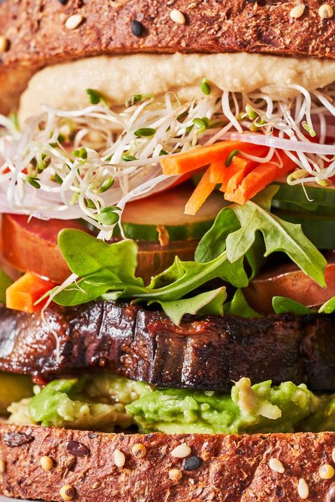 close up of a veggie sandwich with avocado, carrots, pea sprouts, eggplant, cucumbers, and sweet potato