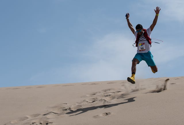 Un corredor de ultramaratón festeja su llegada a una playa.