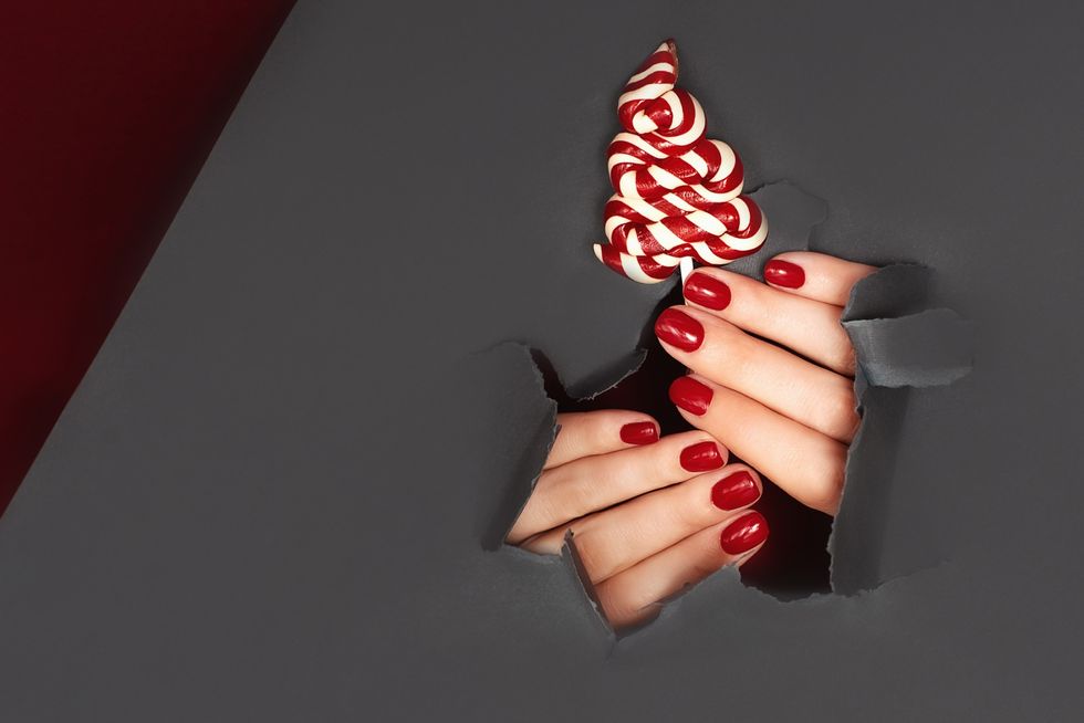 bright festive red manicure on female hands nails design