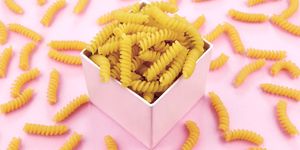 Uncooked italian pasta on pink background.