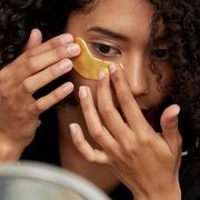 woman applying gold under eye mask