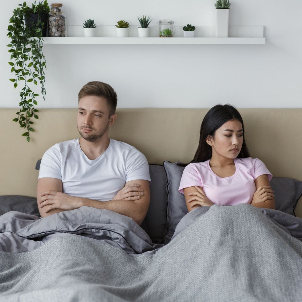 unhappy couple lying in bed uninterested in sexual life indoor