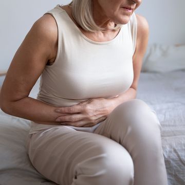 unhealthy woman embracing belly, suffering from strong stomach ache