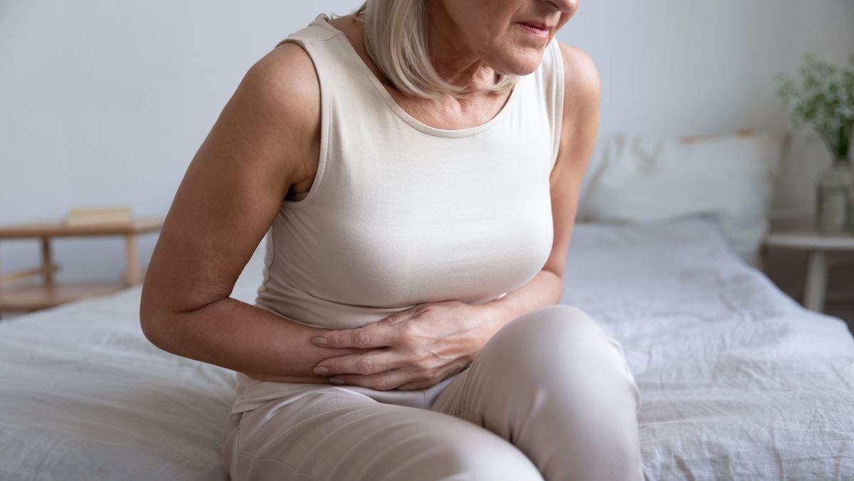 unhealthy woman embracing belly, suffering from strong stomach ache