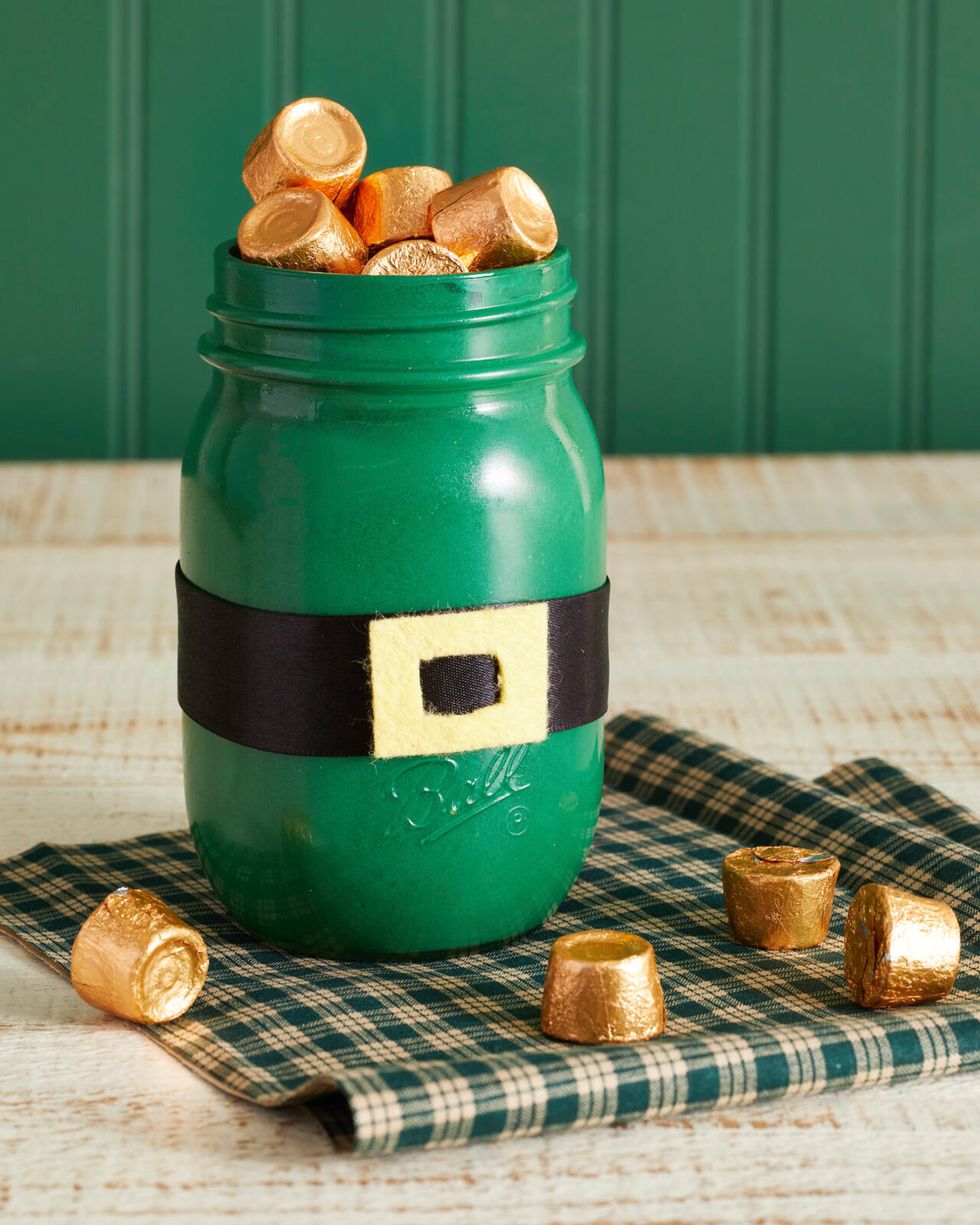 a mason jar painted green with a belt to look like a leprechaun filled with gold wrapped candy