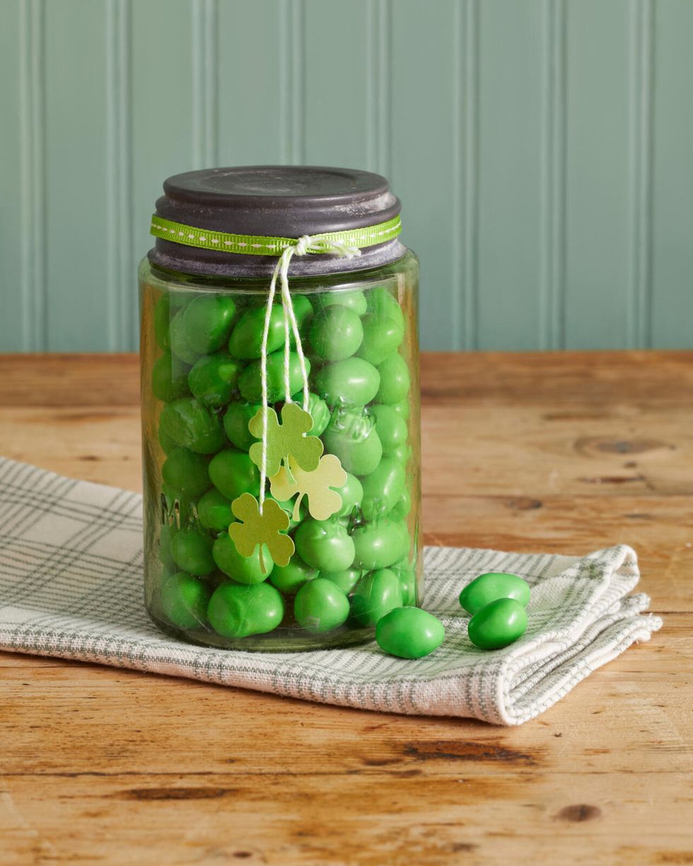 green mason jar filled green candy with four leaf clover tags hanging from the lid