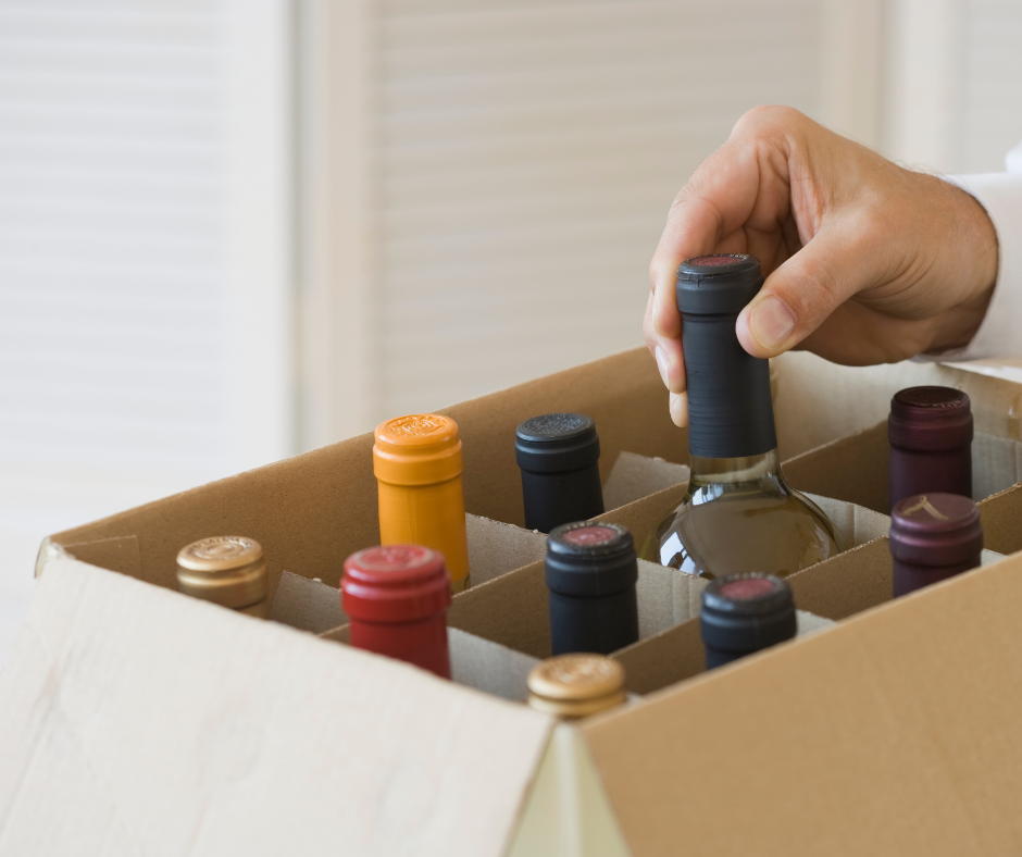 hand reaching for a wine bottle from a box containing various wines